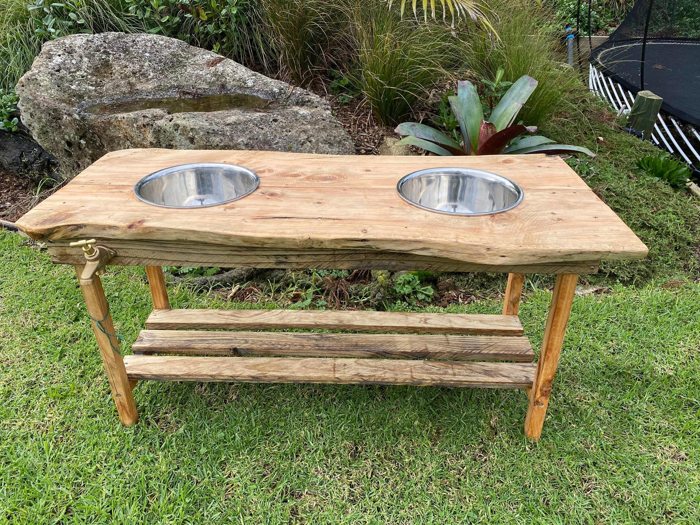 Outdoor wooden play table for children. Made to be used for messy play with sand and mud and water. Outdoor tap that can be connected to a hose for extra fun water play. Made with macrocarpa wood with two stainless steal bowls. 